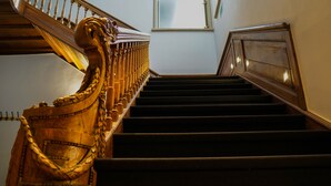 Un escalier en bois, orné de balustres travaillés et doté d’une main courante.