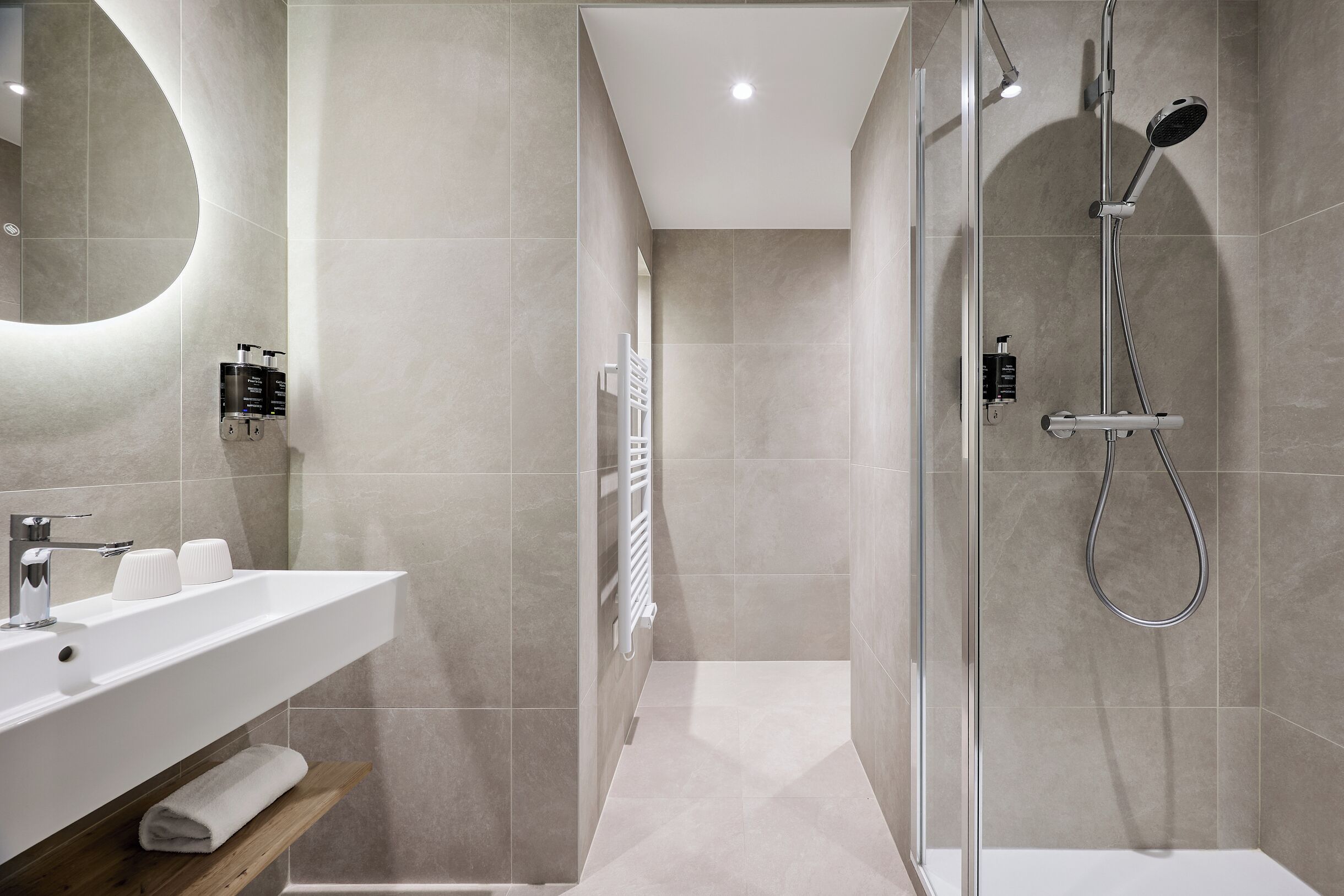 Une salle de bain moderne avec une douche à parois de verre, un lavabo blanc et un miroir.