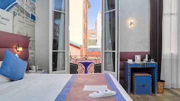 A hotel room with a bed, a desk, a chair, and a view of the cityscape.