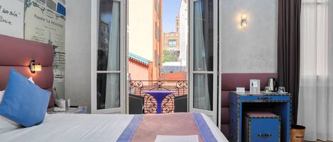A hotel room with a bed, a desk, a chair, and a view of the cityscape.