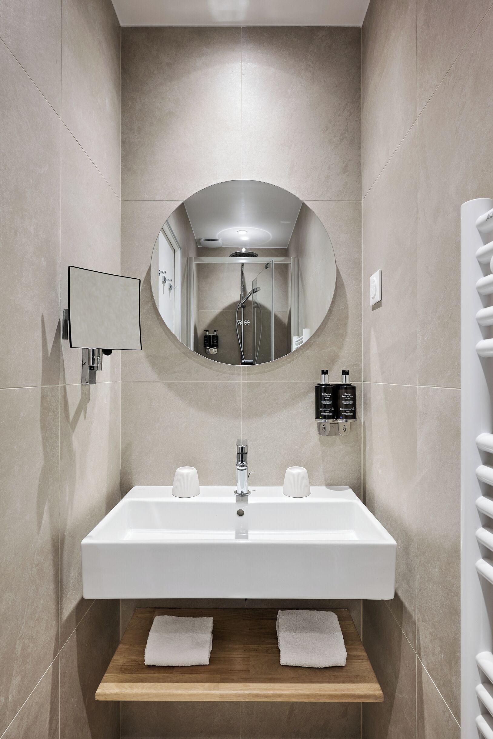 A modern bathroom with a large mirror, a sink, and a shower.