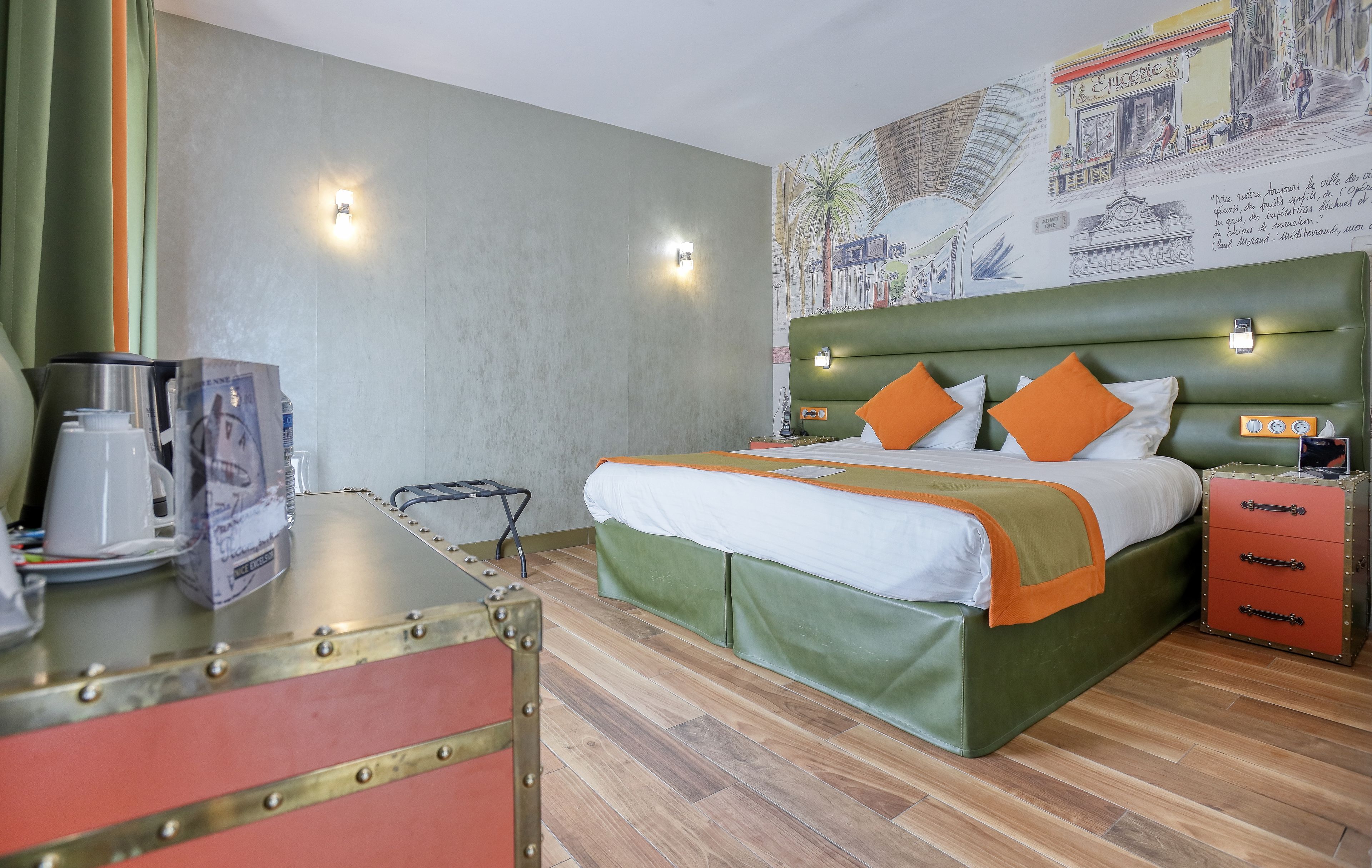 Una habitación de hotel con cama, cómoda, cafetera y una pared decorada con un mural.