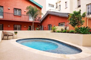 Una piscina rodeada por un muro bajo, con una silla y una pequeña mesa cerca.