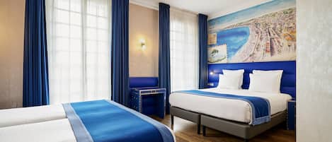 A hotel room with two beds, a mural of a coastal city, and a wooden floor.