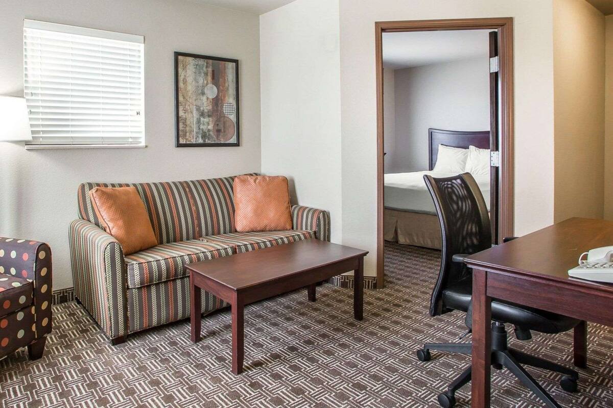 Una habitación de hotel con sofá, una mesita, un escritorio y una cama.