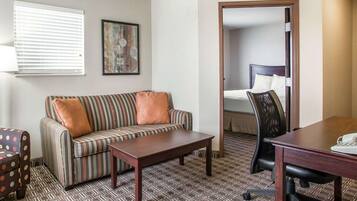 A hotel room with a sofa, a small table, a desk, and a bed.