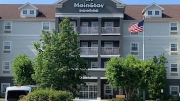 A MainStay hotel with a two-story building, multiple balconies, and an American flag.