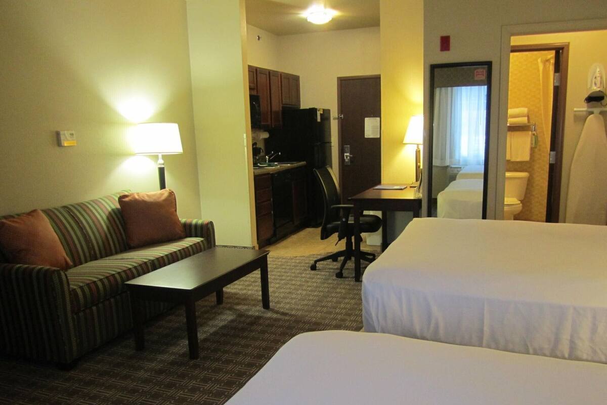 Una habitación de hotel con cama, sofá, escritorio y kitchenette.