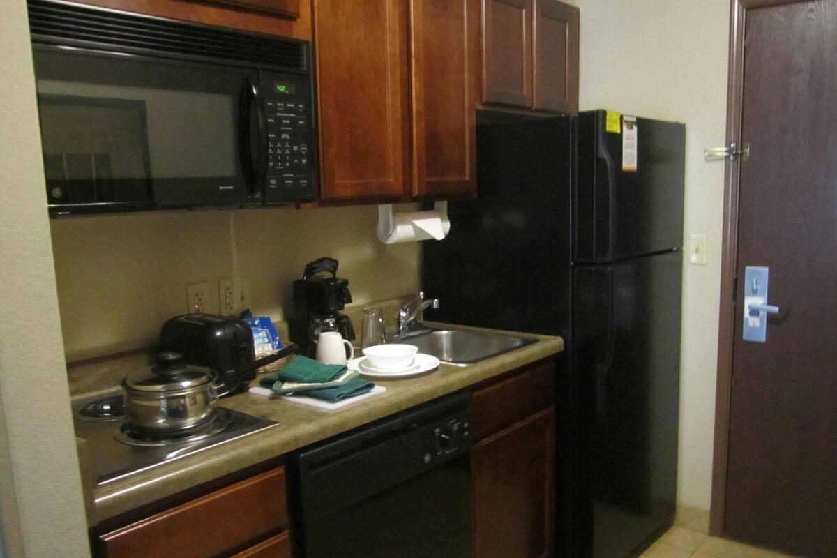 Una cocina compacta equipada con microondas, cafetera, tostadora y refrigerador.
