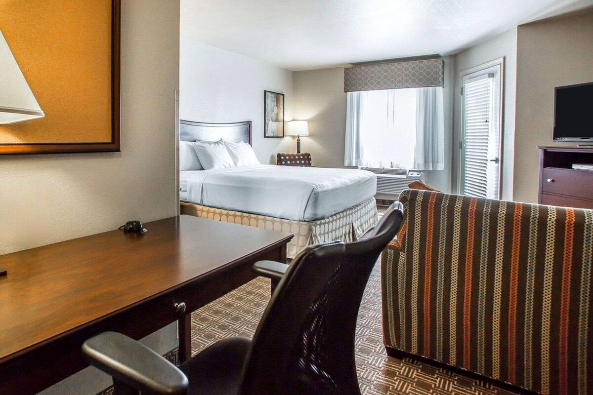 Una habitación de hotel con una cama, un escritorio, una silla, un televisor y una ventana.