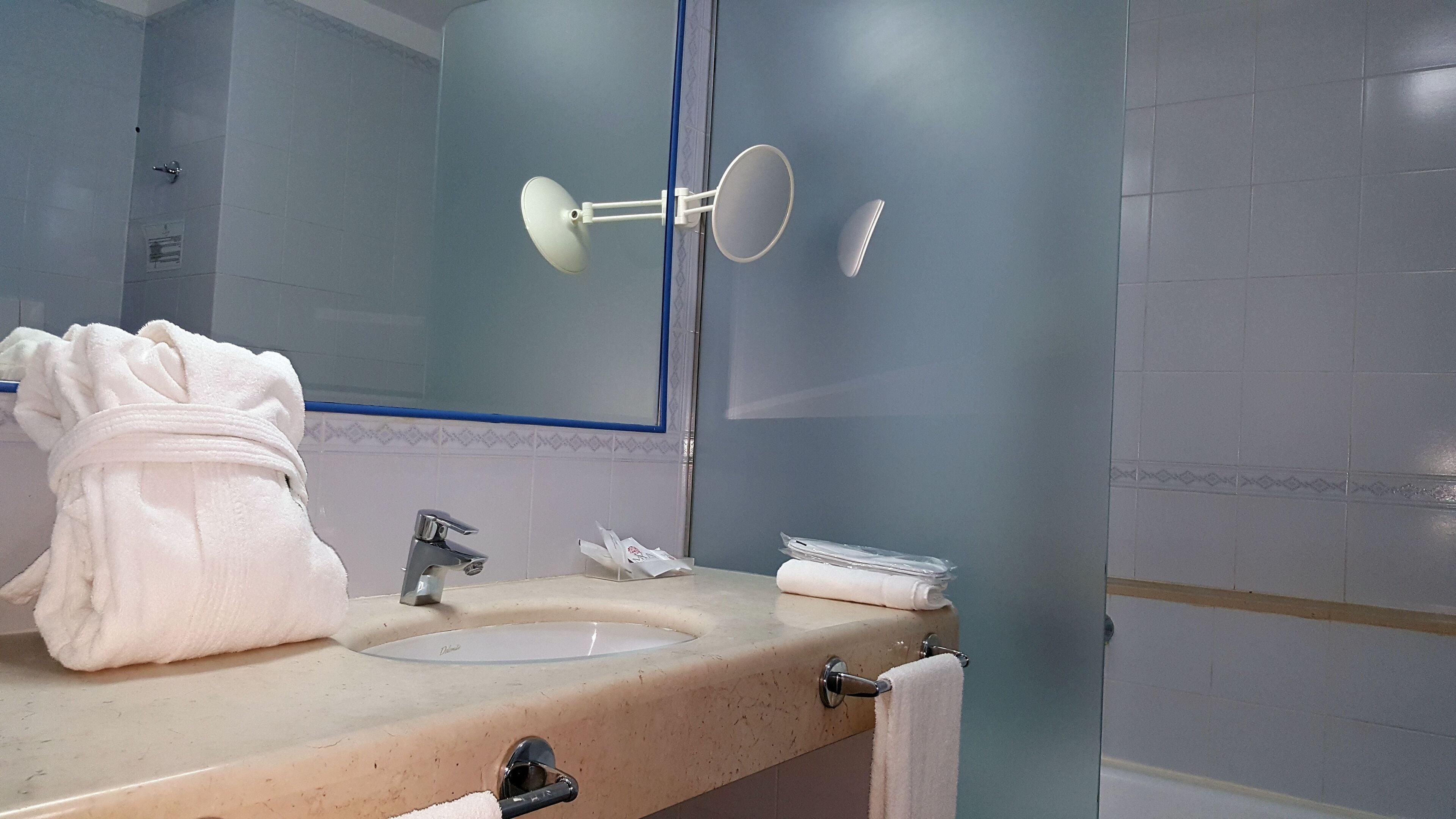 Un baño con lavabo, espejo, toallero y zona de ducha.