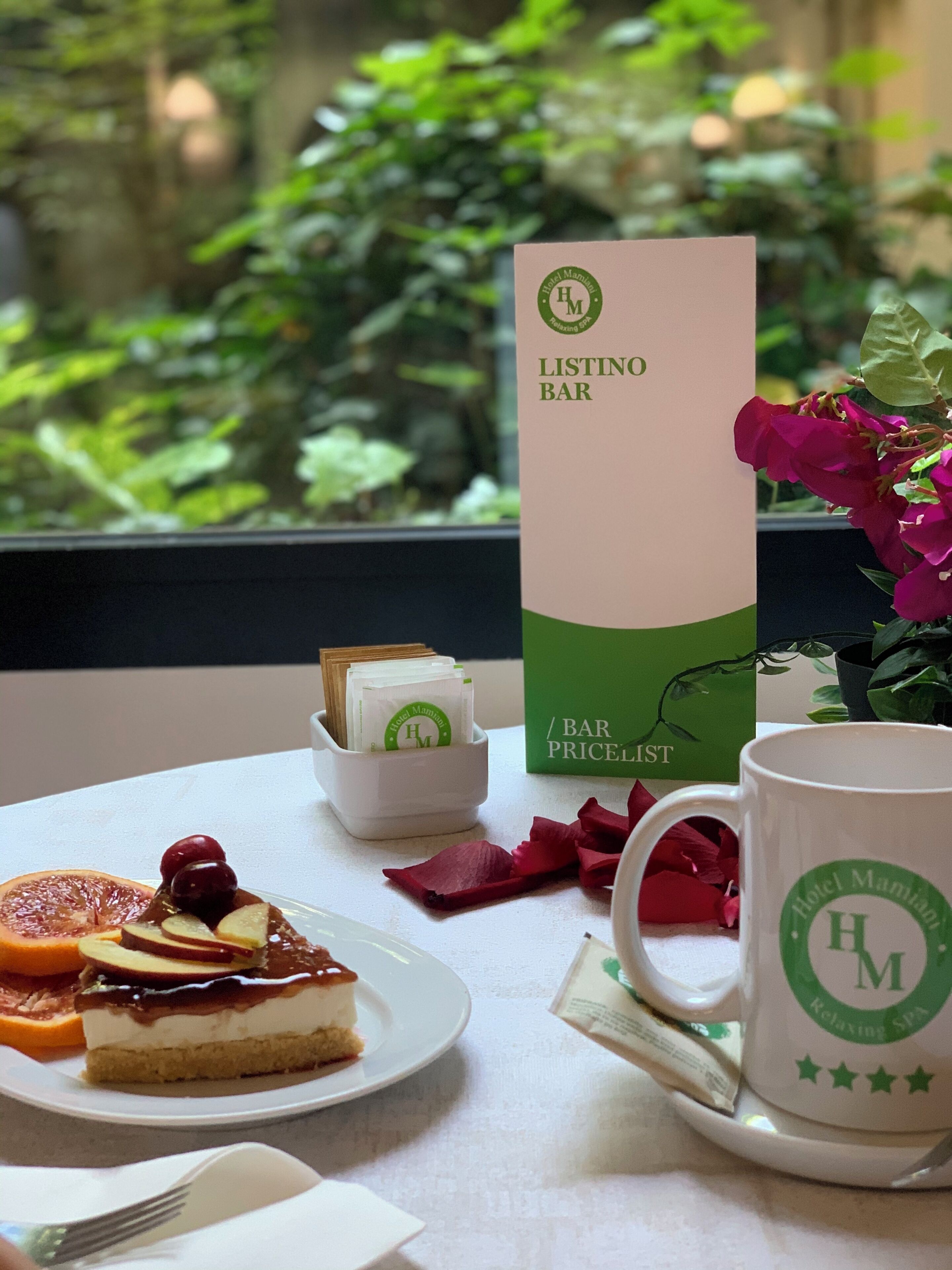 Ein Tisch mit Dessert, einer Tasse, einer Speisekarte und einer kleinen Pflanze.