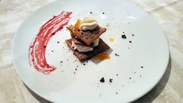 Un postre en un plato blanco con una mancha de salsa roja.