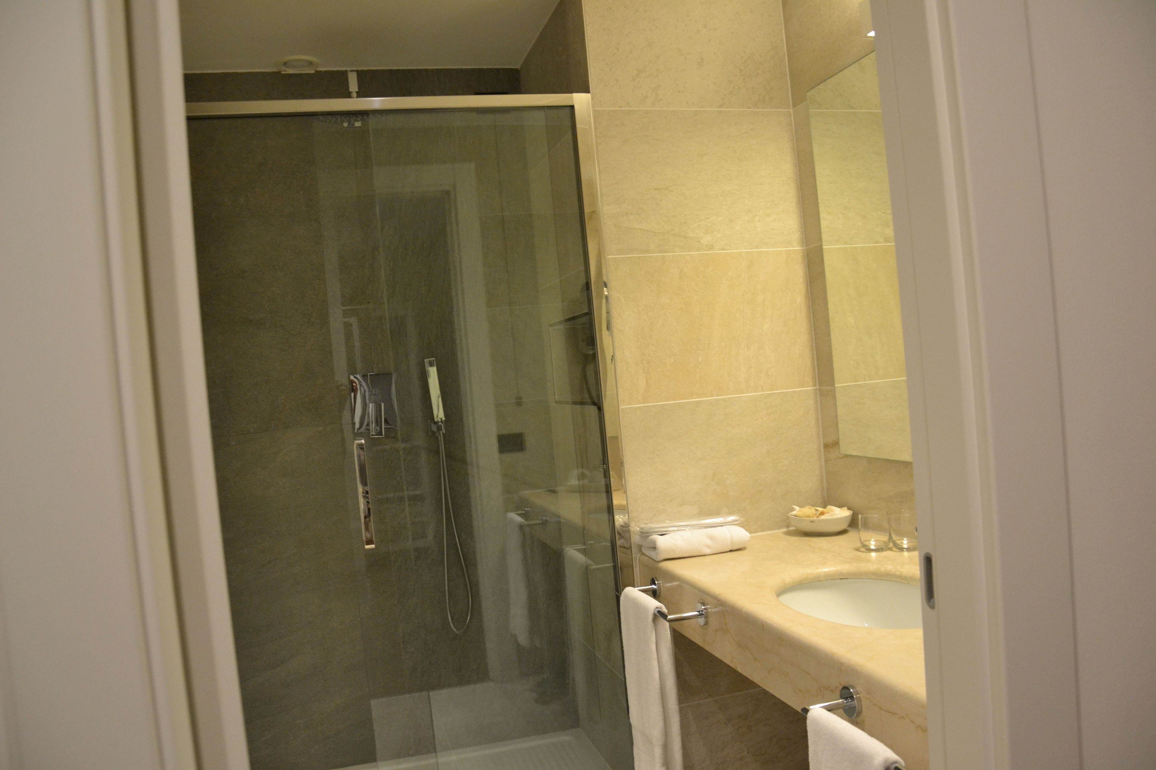 Un bagno moderno con doccia vetrata, un lavandino color beige e uno specchio sopra il lavandino.