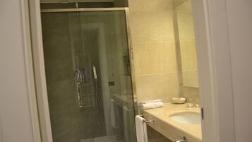 Un bagno moderno con doccia vetrata, un lavandino color beige e uno specchio sopra il lavandino.