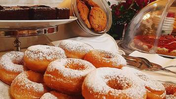 A buffet table with various pastries including donuts and cookies.