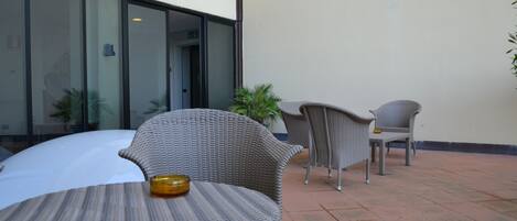 An outdoor patio area with wicker furniture and a glass door entrance.