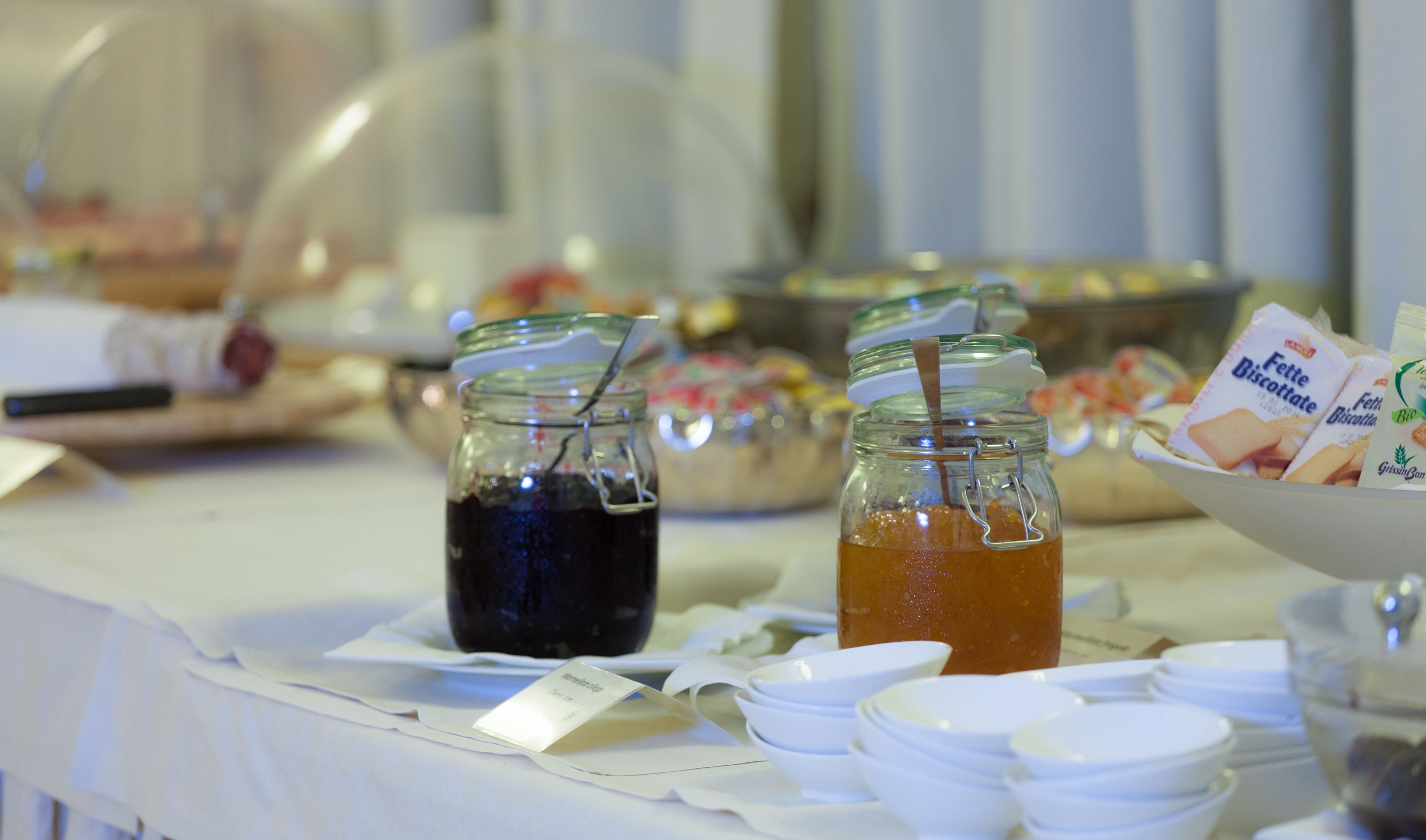 Uma mesa de buffet com diversos alimentos e bebidas, incluindo potes de bebidas e embalagens de biscoitos.