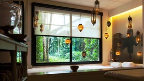 Una habitación con un ventanal grande, varias lámparas colgantes y vistas al exterior con vegetación.