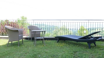 Un balcone con sedie in vimini e una poltrona, affacciato su un panorama suggestivo.