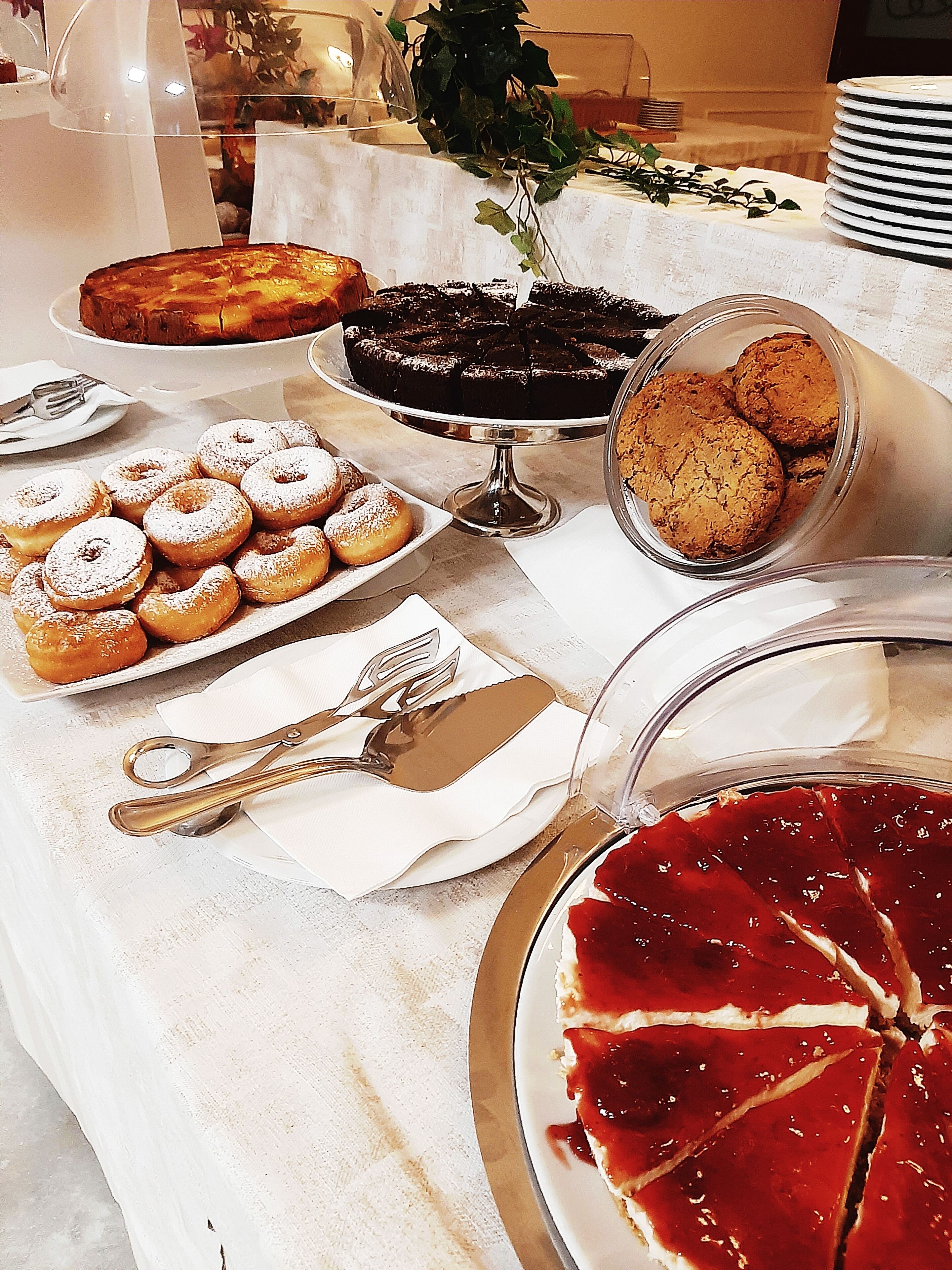 Una mesa de bufé con diversos postres, incluyendo rosquillas, pastel y tarta.