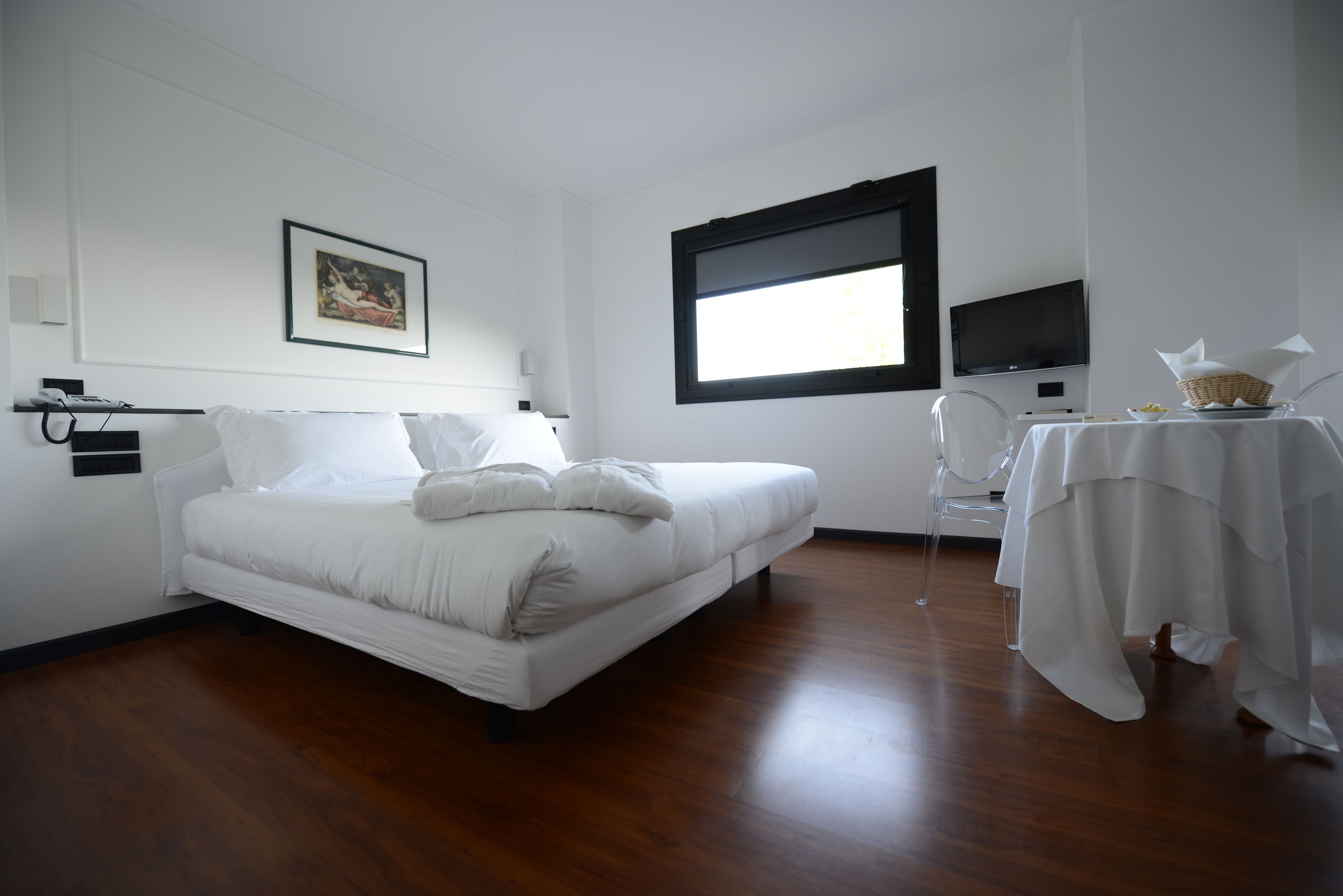 Una habitación de hotel con cama, escritorio, silla, televisión y ventana.