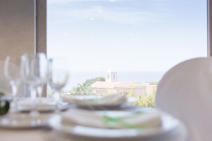 Una mesa de comedor con platos y vasos, una silla y vistas a un edificio con una torre a través de una ventana.
