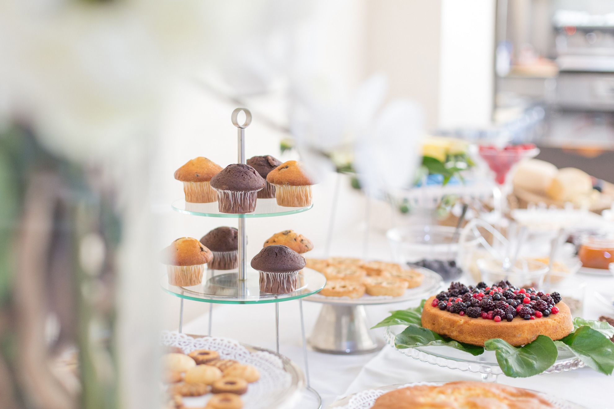 A dessert display with various pastries and a cake topped with berries.