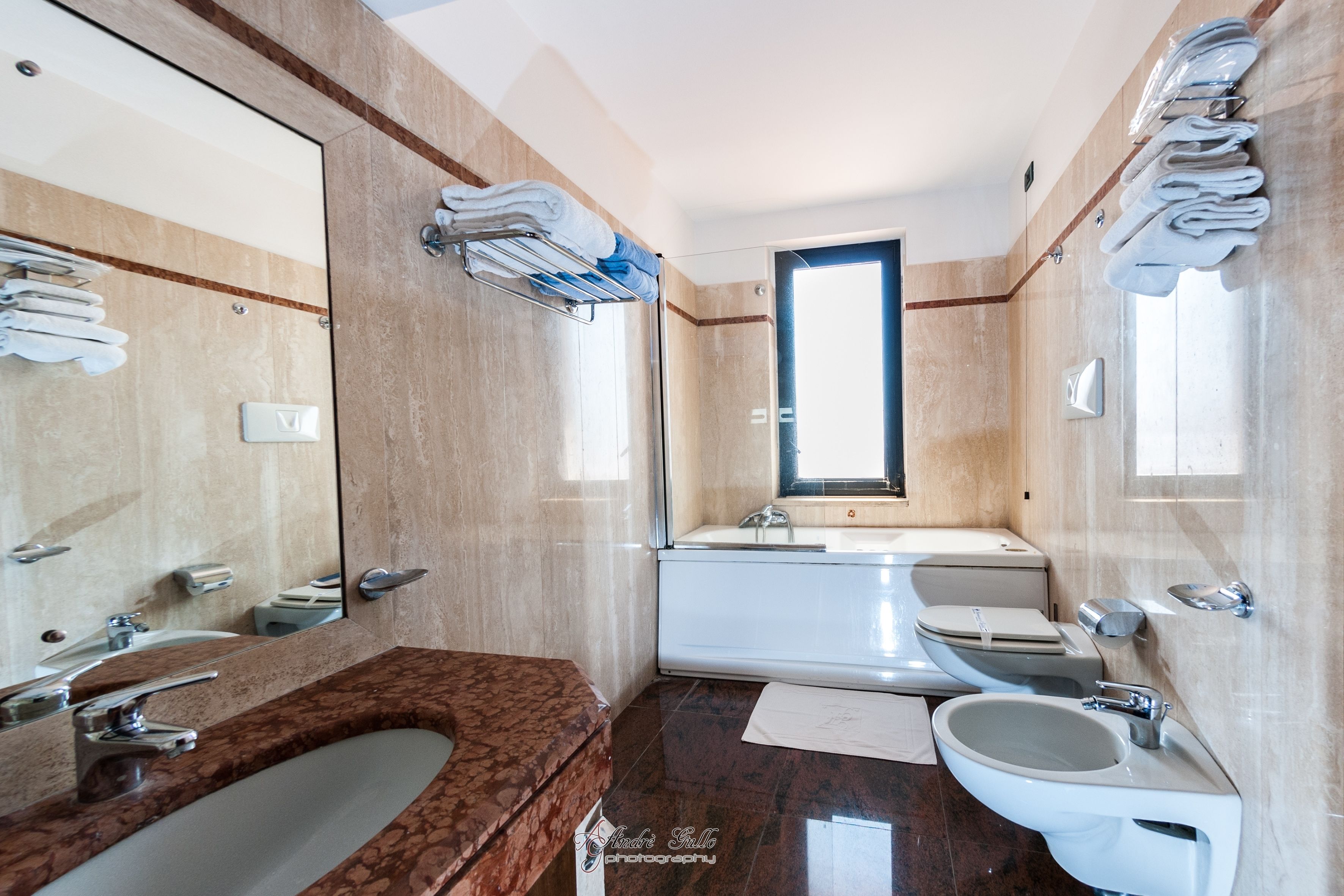 Un bagno moderno con un vanità in marmo, un lavandino, uno specchio e una vasca da bagno.