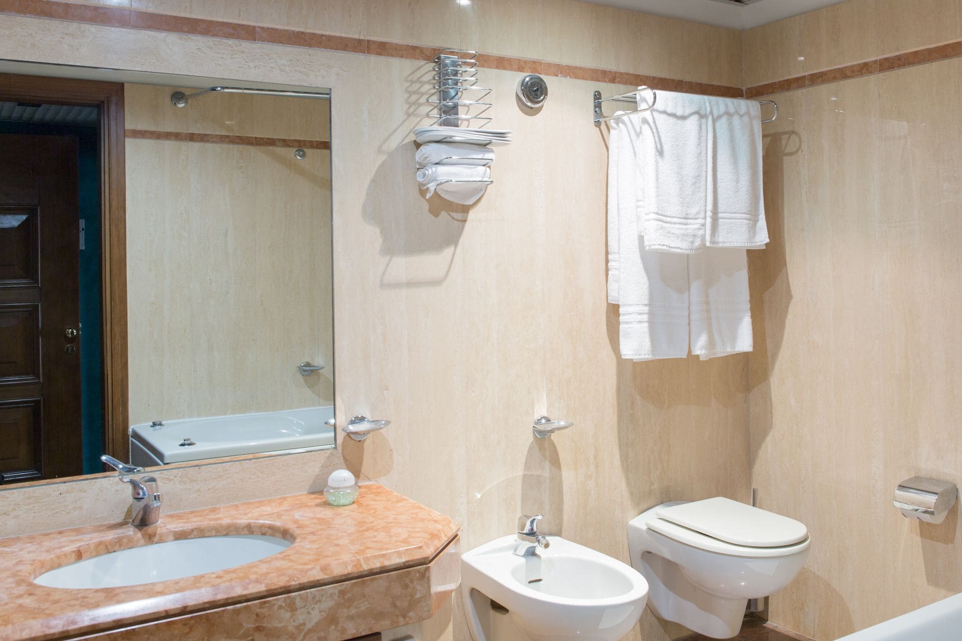 Un baño con lavamanos, bidé, inodoro y un perchero para toallas.