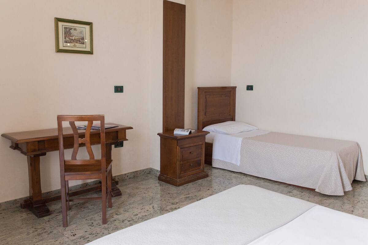 Un dormitorio con un escritorio de madera, una silla, una cama y una mesita de noche.