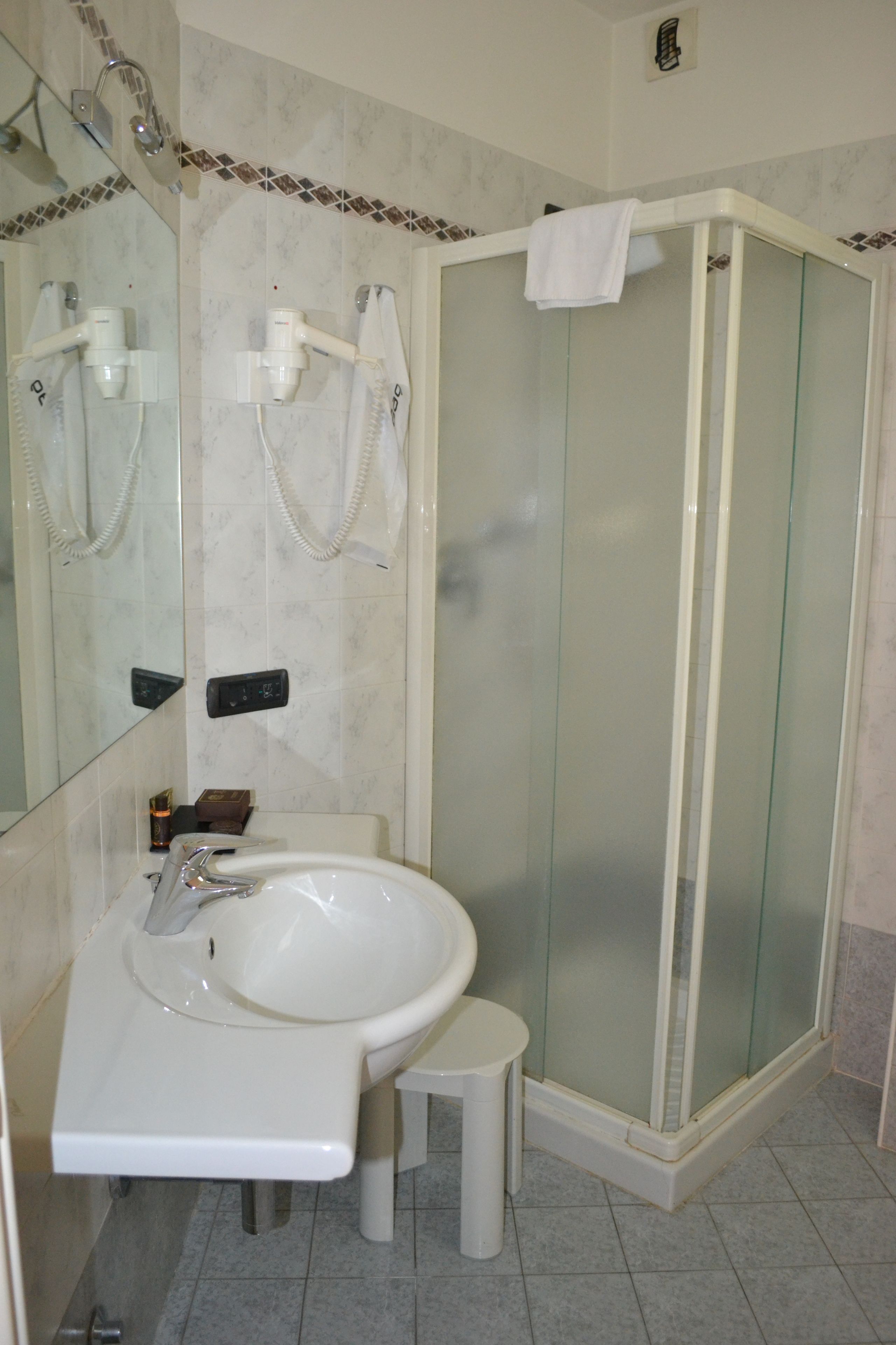 Un baño con ducha acristalada, un lavabo blanco y un espejo.