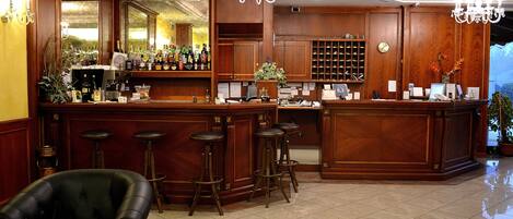 Zona de bar con taburetes de madera, mostrador y candelabro.