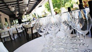 A row of empty wine glasses on a table in a restaurant with a modern ceiling design and indoor plants. - Palazzo Virgilio (Brindisi)