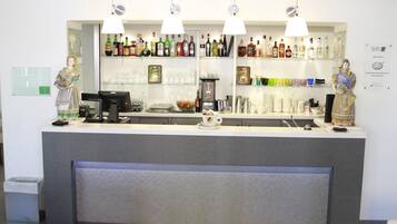 Una zona de bar con mostrador, varias botellas, vasos y una máquina de café.