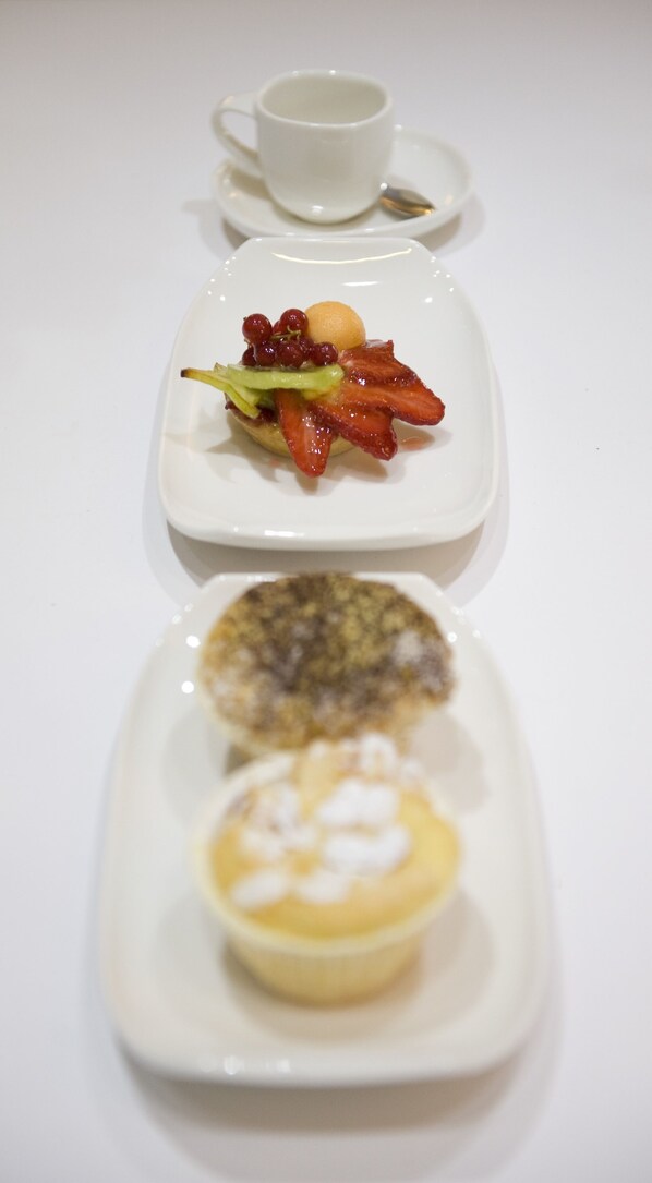 Una mesa blanca con tres platos cuadrados, cada uno con distintos alimentos.
