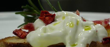 A breakfast dish with poached eggs, bacon, and a sprig of rosemary.