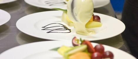 Iemand serveert een dessert op een wit bord met een lepel.