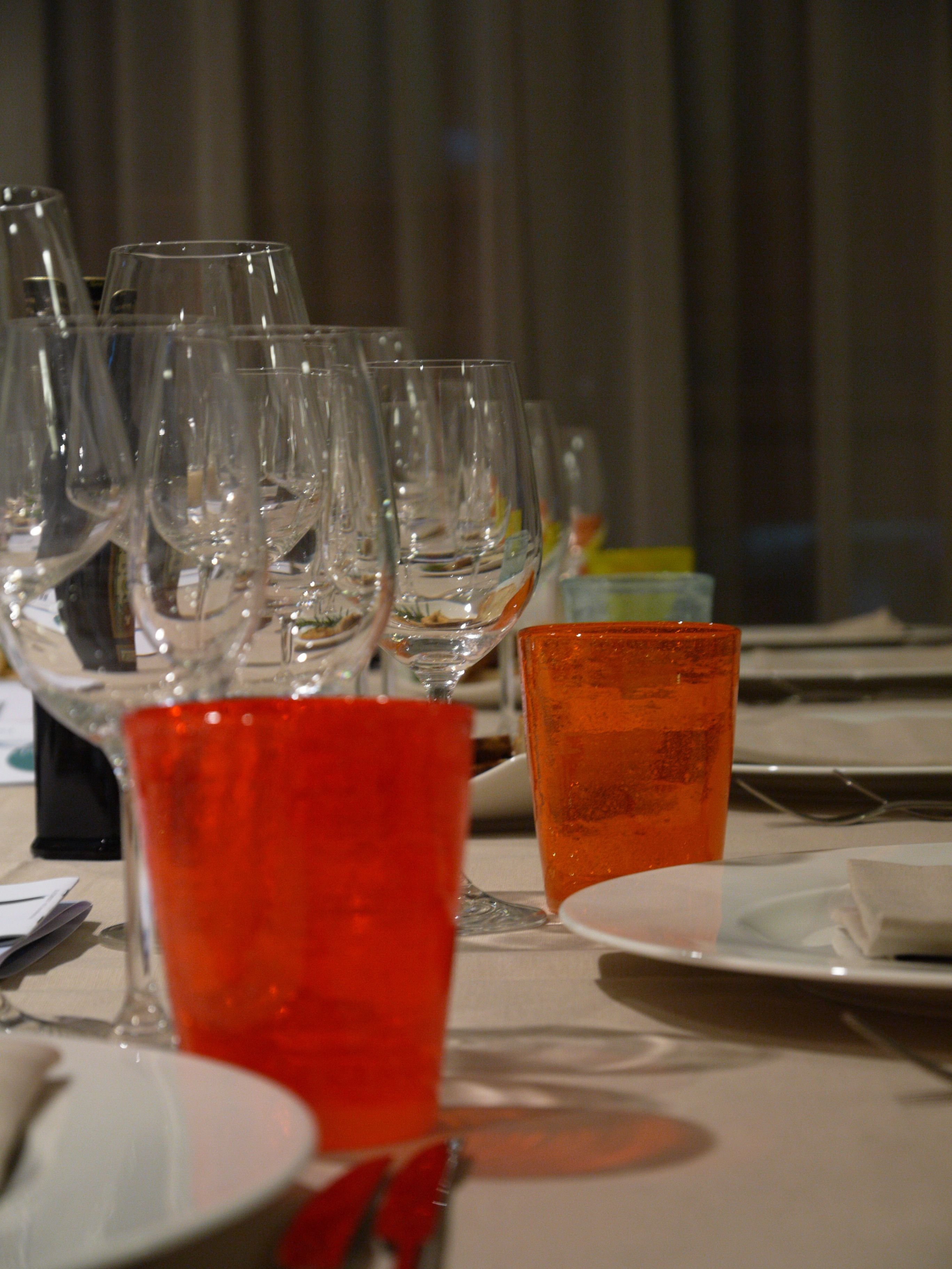 A table set with multiple wine glasses and a few red glasses, likely for cocktails.