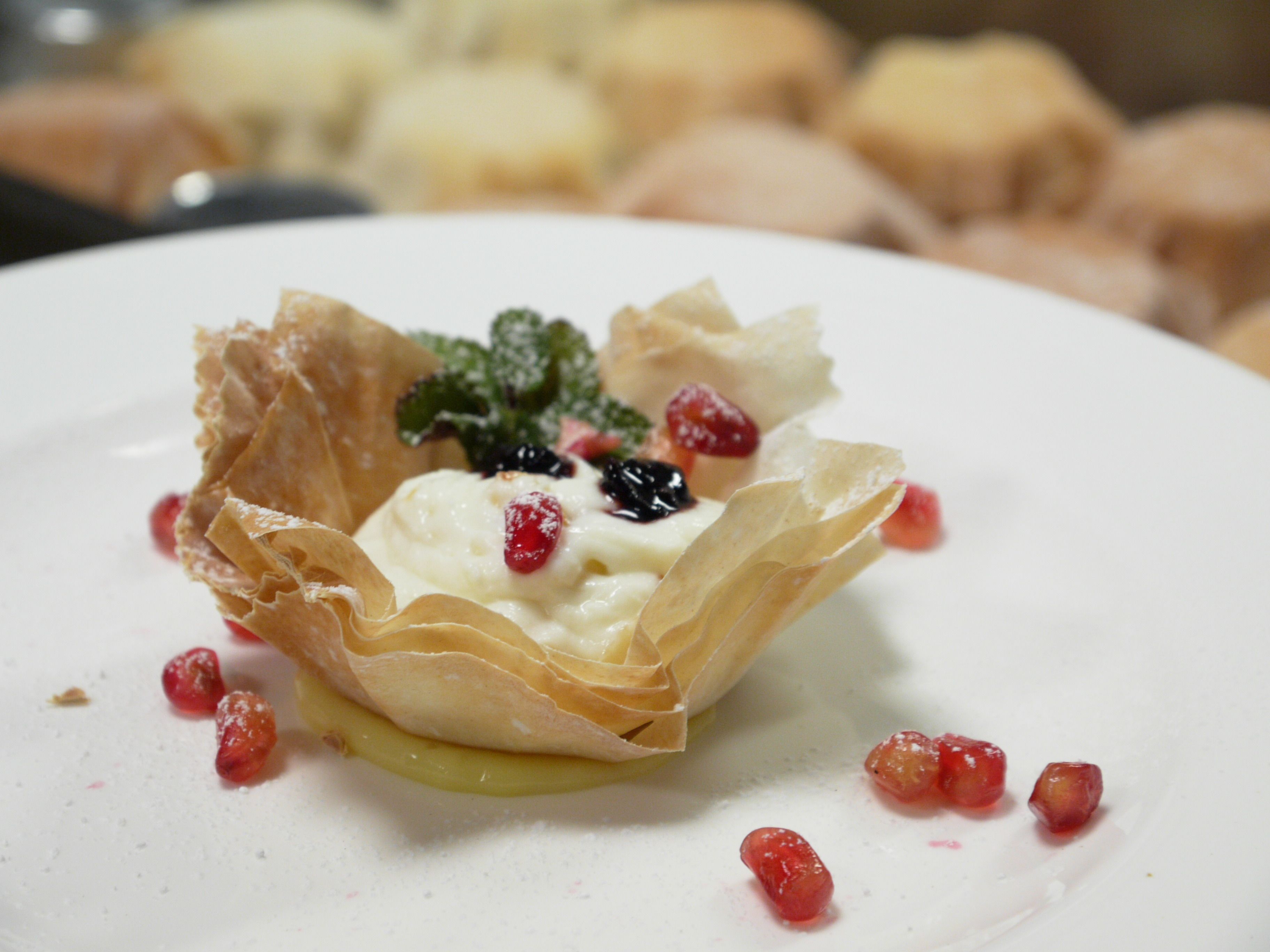 Dessert auf einem Teller mit cremiger Glasur, Beeren und einem Mürbeteigboden.