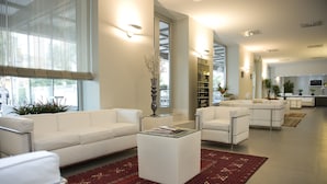 A modern living room with white sofas, a glass coffee table, and a red patterned rug. - Palazzo Virgilio (Brindisi)