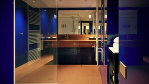 Un baño de hotel moderno con separador de vidrio, tocador de madera y espejo.