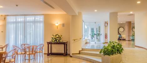 A spacious lobby with a reception desk, seating area, and a staircase leading to upper floors.