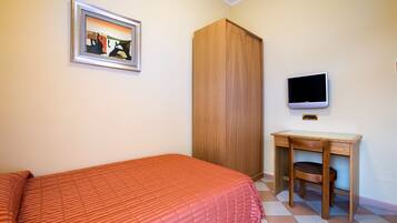 Un dormitorio con una cama, un armario de madera, un escritorio con silla, un televisor y un cuadro en la pared.