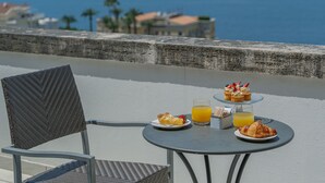 A table with breakfast items including pastries, a glass of orange juice, and a plate of food, set on a balcony overlooking a coastal area. - Grand Hotel Moon Valley (Vico Equense)