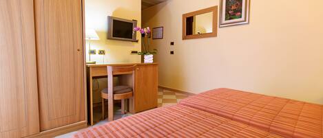 A hotel room with a bed, a desk, a chair, a television, and a framed picture on the wall.