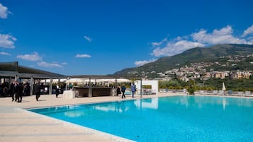 A swimming pool with a clear view of a town and hills in the background.
