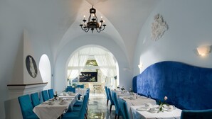 A restaurant with white walls, blue chairs, and tables set for dining. - Gatto Bianco Hotel & SPA (Capri)