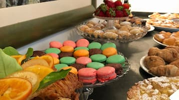 A buffet table with various pastries, including croissants, macarons, and a pie.