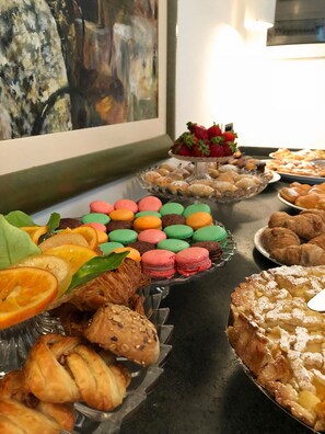 A buffet table with various pastries, including croissants, macarons, and a pie.
